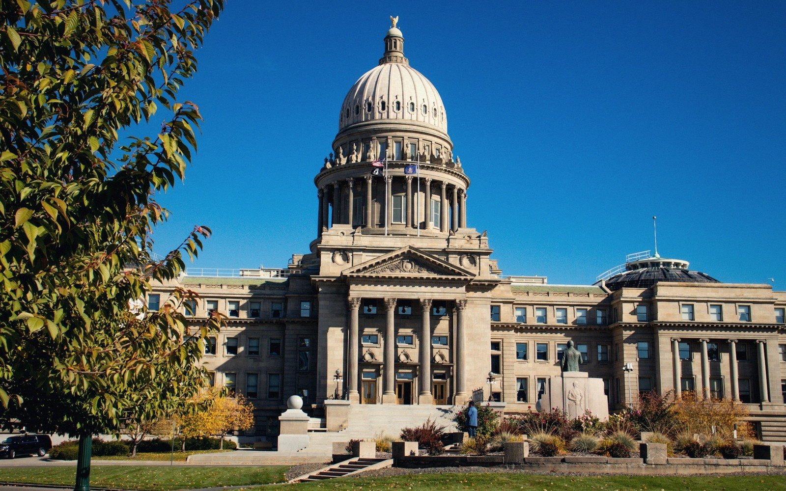 Domed state capitol building with columned entrance under a clear blue sky